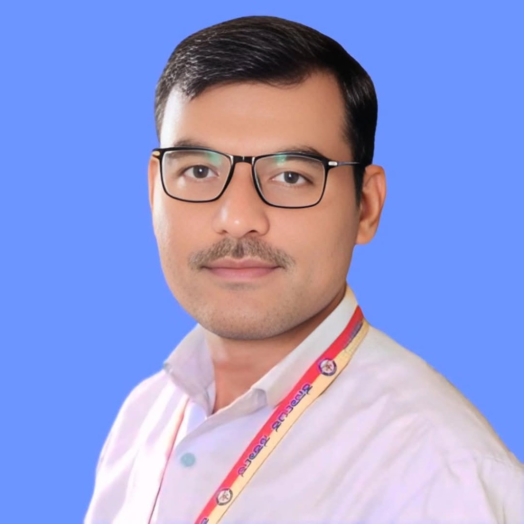 Portrait of Rajashekhar Ragati wearing glasses and a white shirt against a blue background